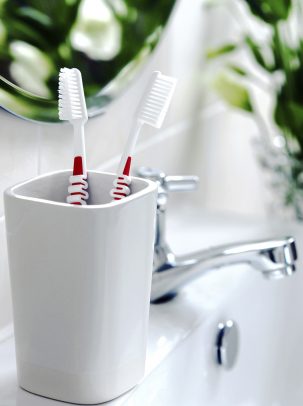 two toothbrushes in a cup by the sink