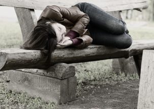 young girl sleeping on a bench