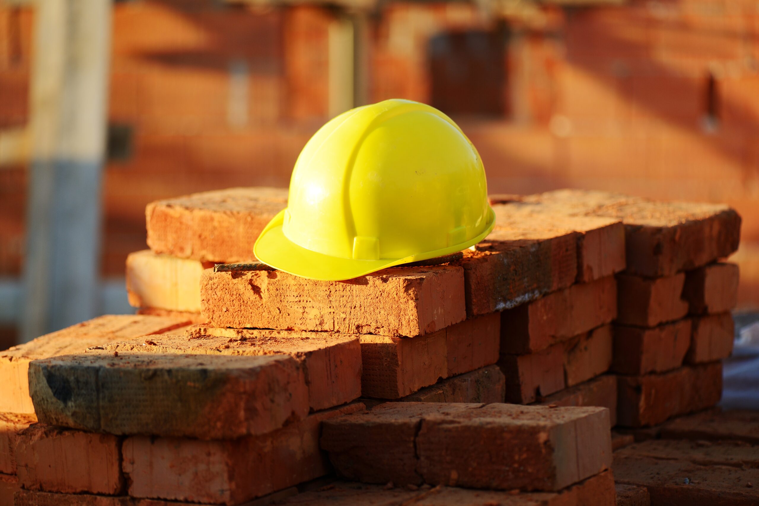 builders yellow helmet on a pile of bricks