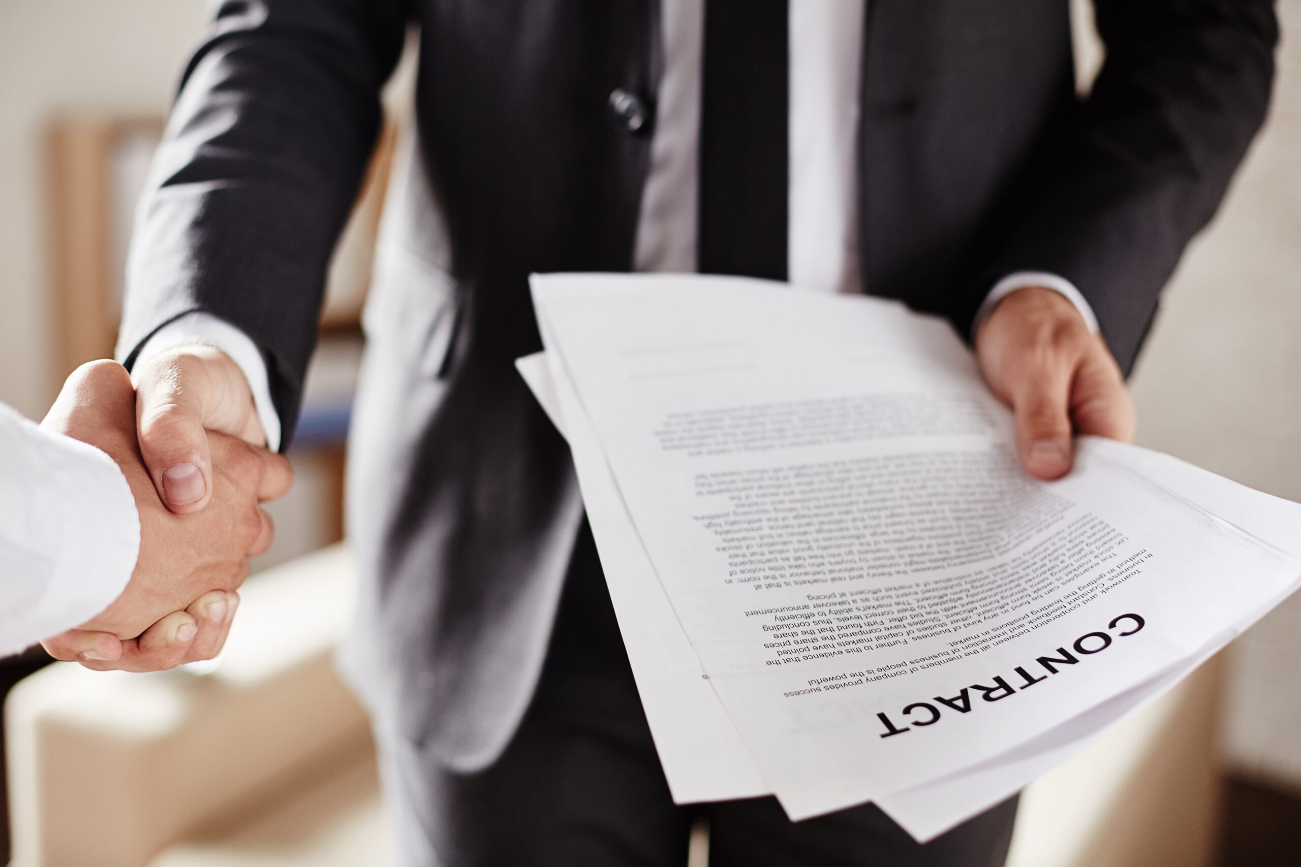 Businessmen shaking hands with contract