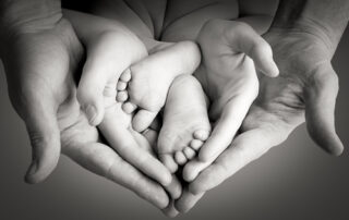 adult hands (parents) protecting baby feet