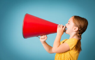 girl talking through a red horn