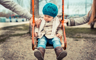 girl on swing being tugged by both parents, separation concept