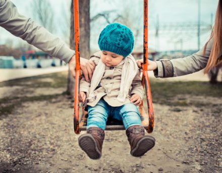 girl on swing being tugged by both parents, separation concept