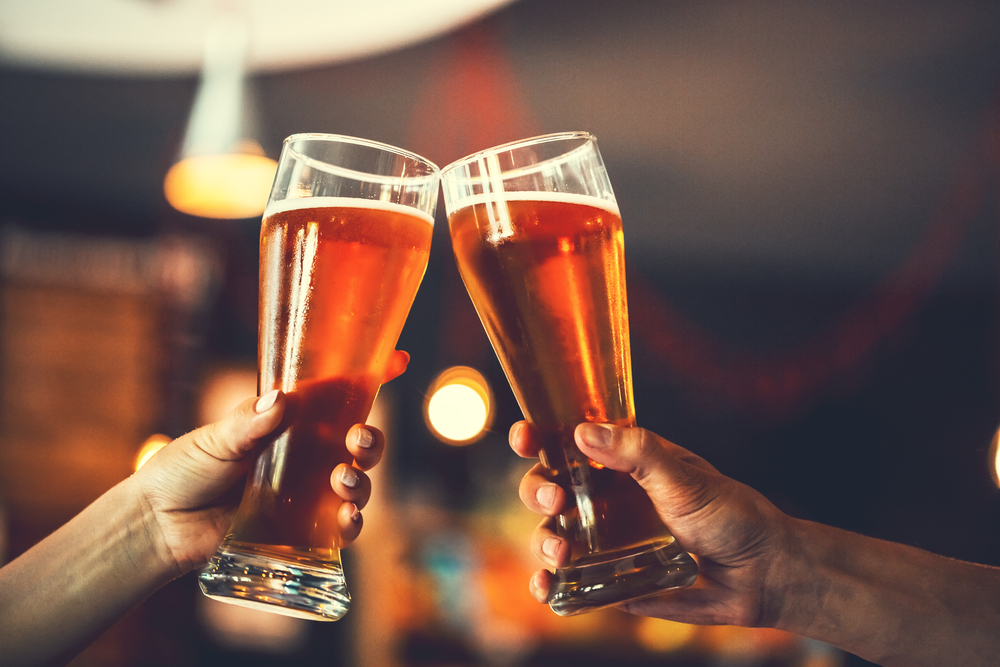 two friends cheering with two pints