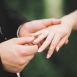 groom putting wedding ring on brides finger