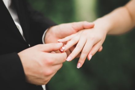 groom putting wedding ring on brides finger