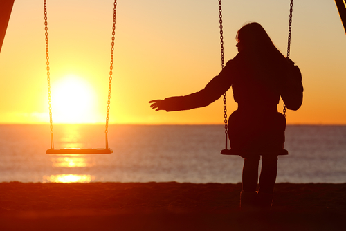 woman sitting alone on a swing at sunset