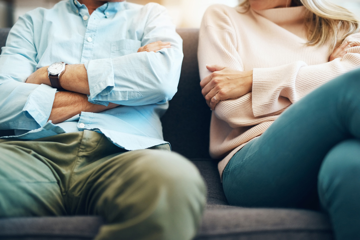 Mature couple sitting on the sofa with their arms folded after an argument