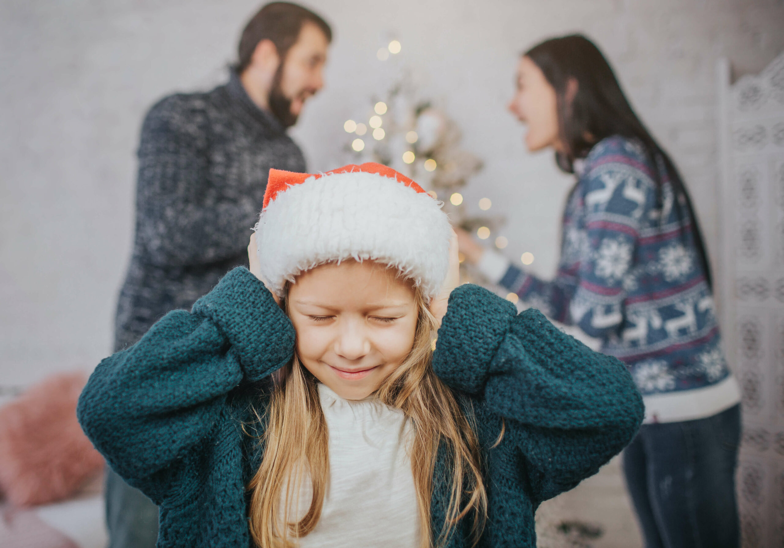 Girl hands over ears as couple quarreling at Christmas