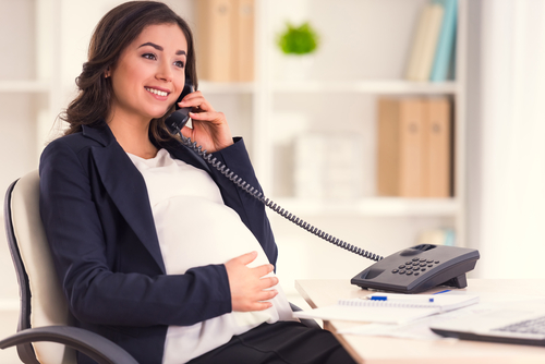 Happy Pregnant Woman Talking On The Phone while working